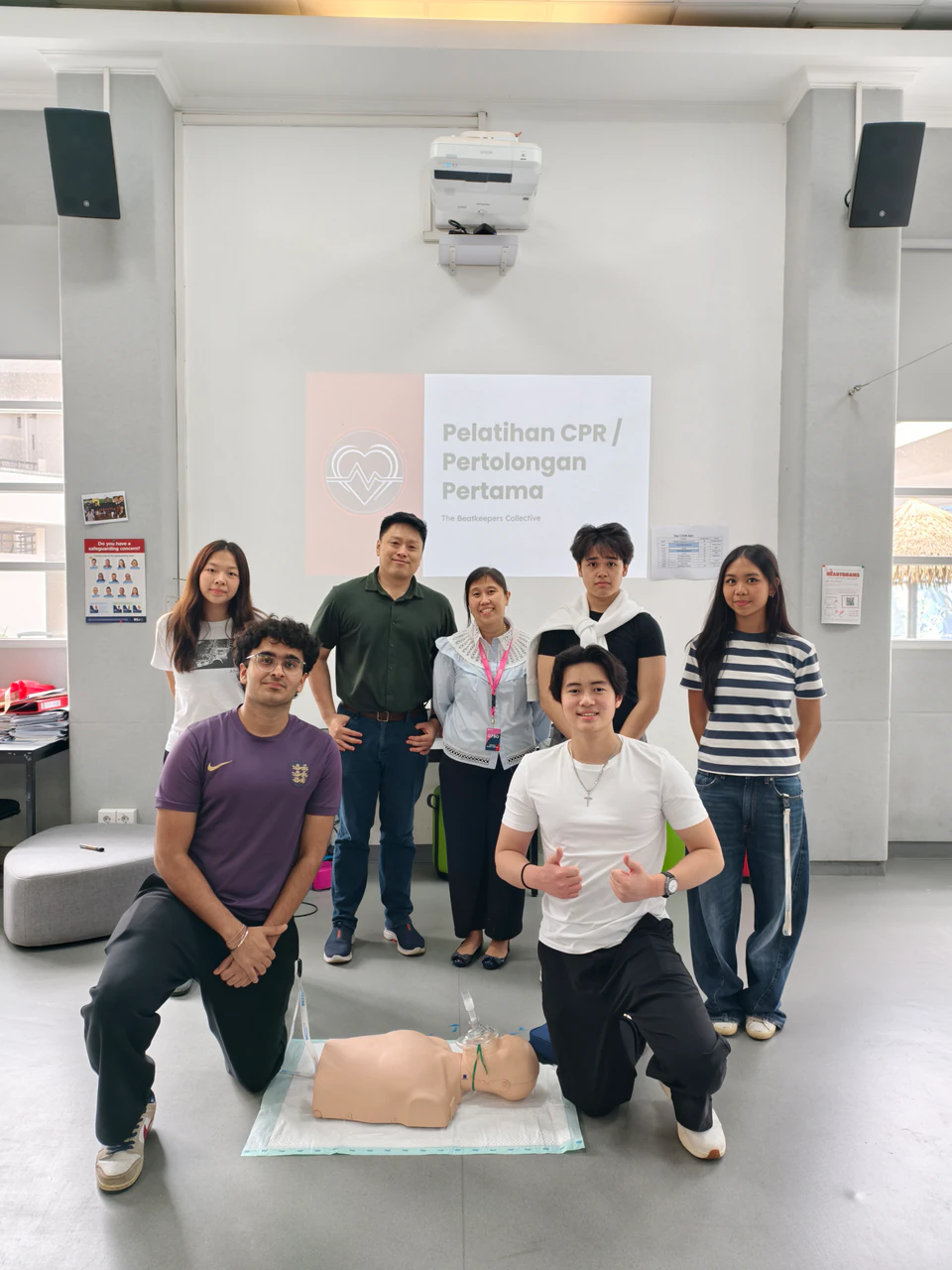 Beatkeepers workshop volunteers posing beside a CPR training manikin