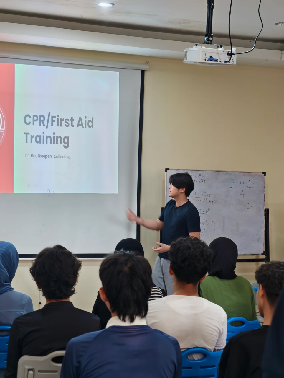A volunteer presenting CPR and first aid training to students in a classroom