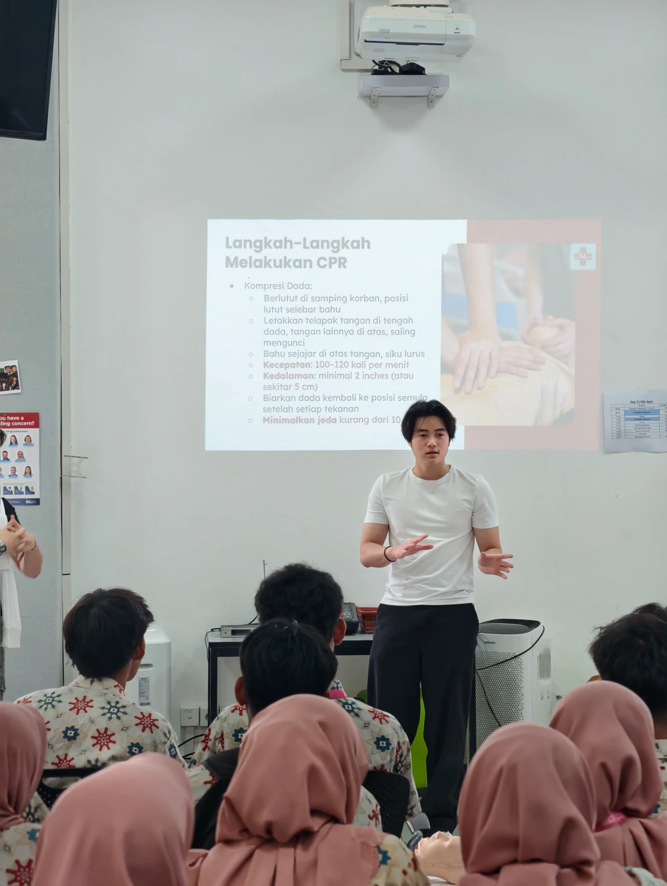 A Beatkeepers volunteer explaining CPR steps to a seated group of students