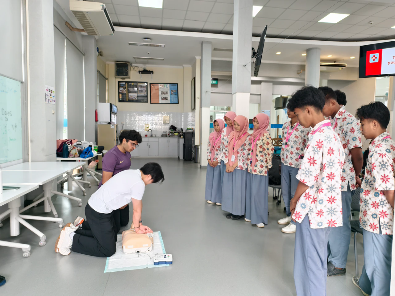 A student practicing CPR on a manikin while classmates observe